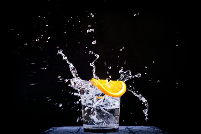 splash of water in drinking glass with sliced lemon
