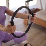 MZ세대부터 중장년층까지… 필라테스로 활기찬 일상 가꾸기 a woman sitting on the floor holding a steering wheel